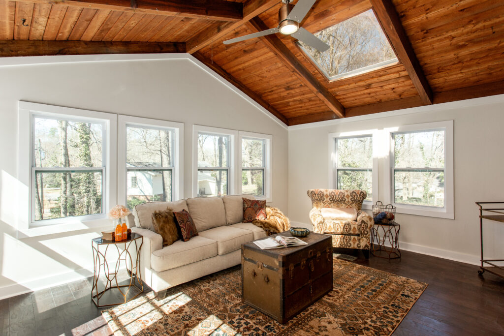 Sunroom addition featuring a vaulted wood plank ceiling, large windows, skylights, and a cozy seating area with patterned area rug, room addition by Parsons Mission Construction