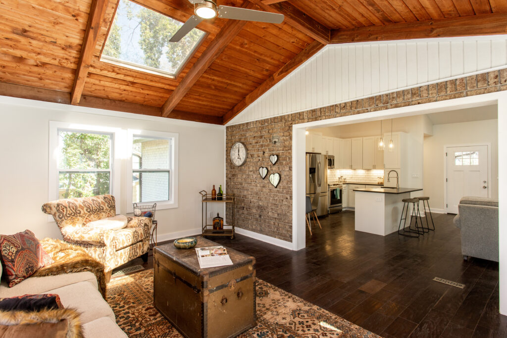 Open sunroom addition featuring a vaulted wood plank ceiling, skylights, large windows, and a view into the adjacent living area, room addition by Parsons Mission Construction