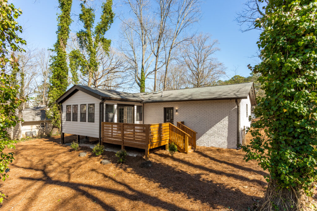 Renovated home exterior featuring white siding, a wood deck with steps, exterior renovation by Parsons Mission Construction