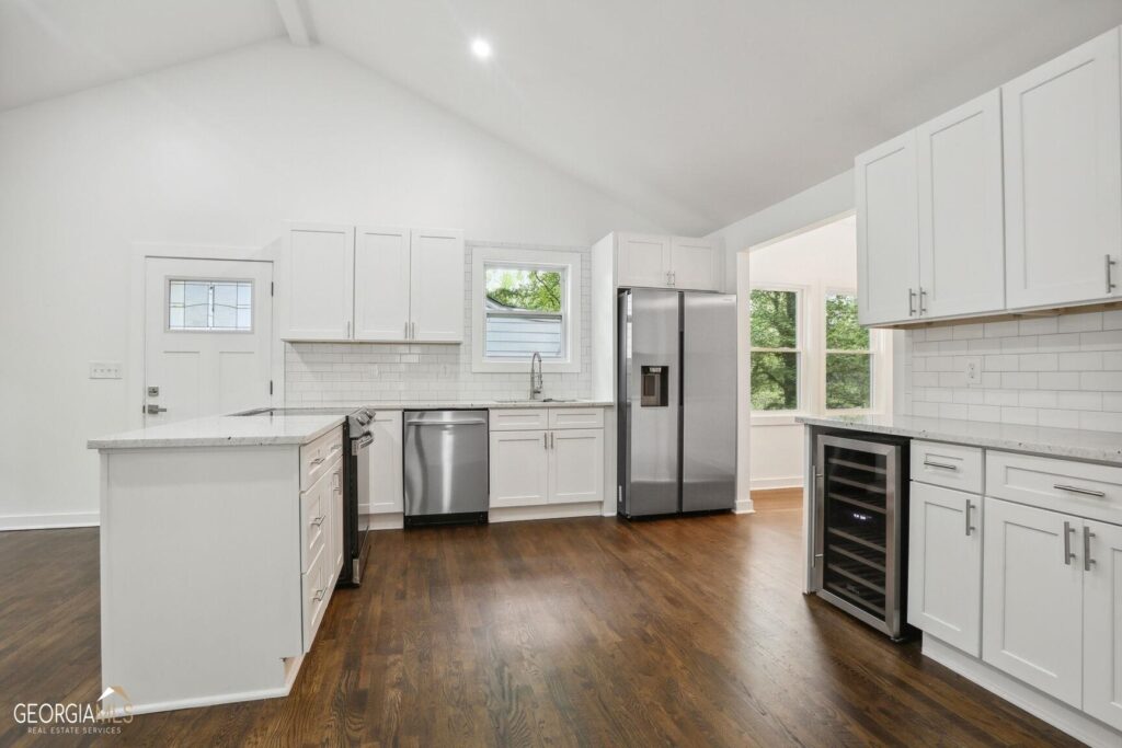Renovated kitchen featuring white cabinetry, dark hardwood floors, and stainless steel appliances including a French door refrigerator, kitchen remodeling by Parsons Mission Construction