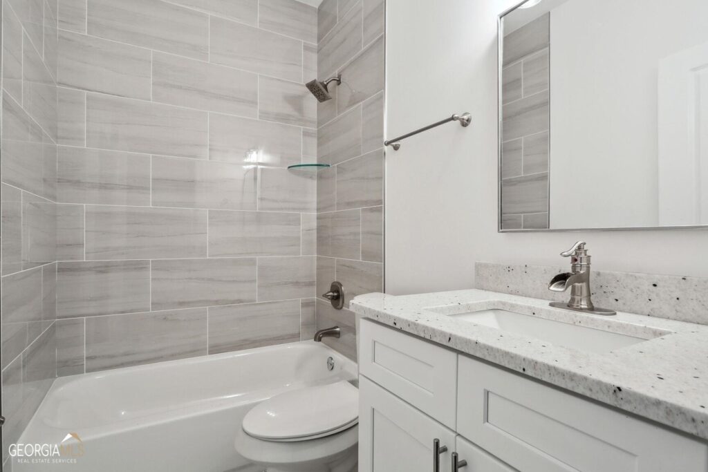 Renovated bathroom featuring gray tile walls, a soaking tub, and a white vanity with storage, bathroom remodeling by Parsons Mission Construction