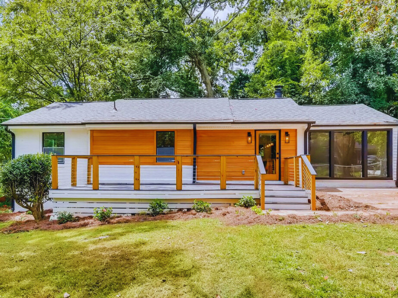 Full exterior view of a mid-century modern home with white and wood paneling, large windows, and a green lawn, exterior renovation by Parsons Mission Construction