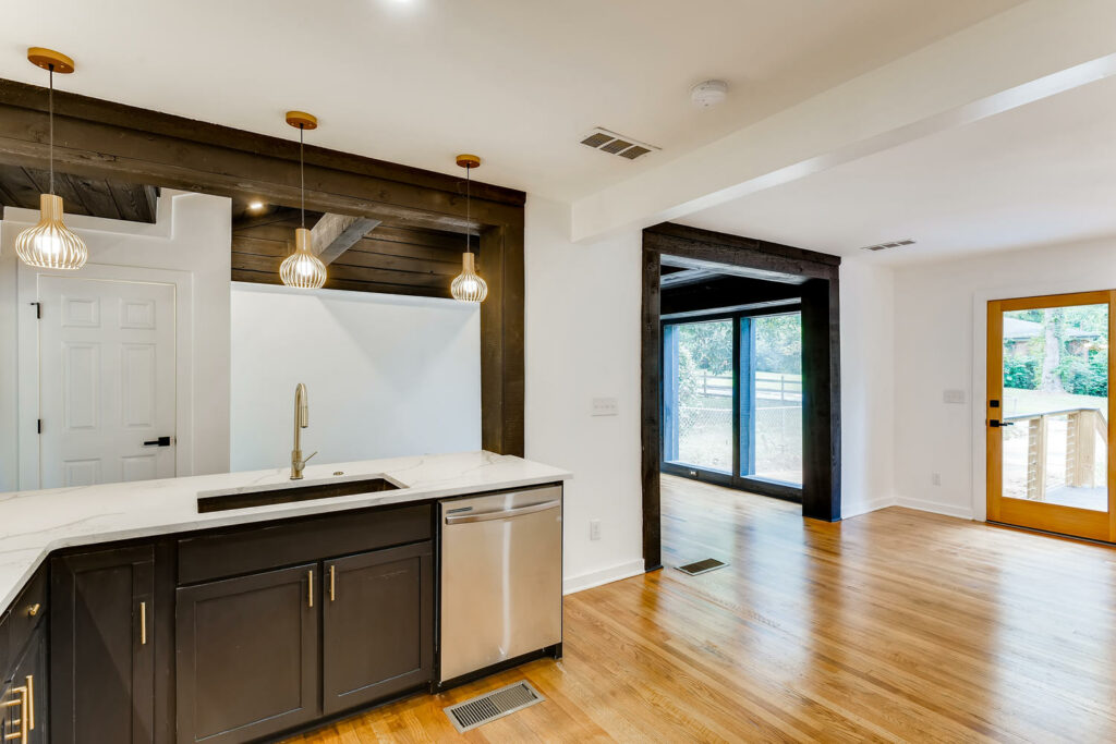 Renovated kitchen featuring dark cabinetry, light countertops, hardwood floors, and a sliding glass door leading to an outdoor space, kitchen remodeling by Parsons Mission Construction