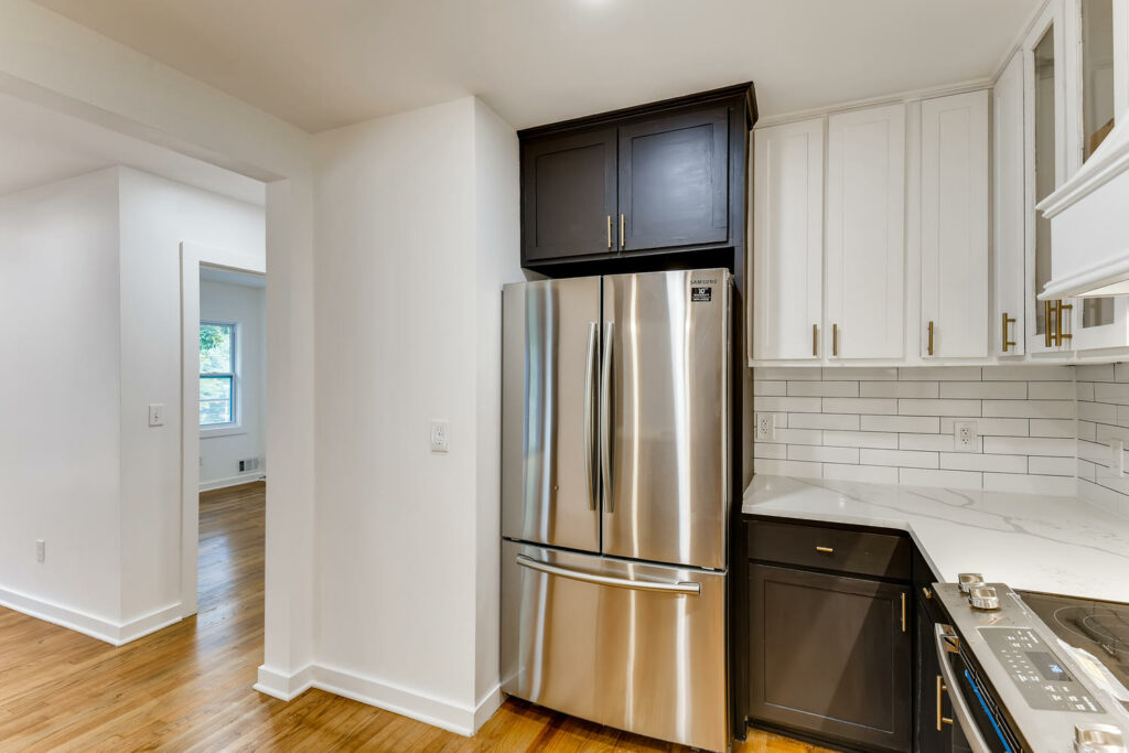Renovated kitchen featuring dark upper cabinets, white lower cabinetry, subway tile backsplash, and a stainless steel French door refrigerator, kitchen remodeling by Parsons Mission Construction