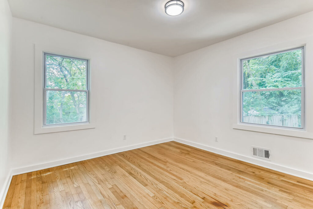 Renovated interior room featuring light hardwood floors, white walls, and a large window providing natural light, home renovation by Parsons Mission Construction
