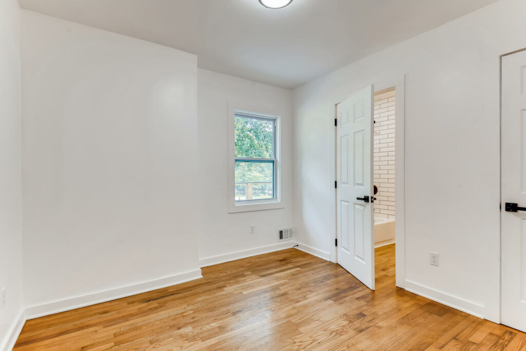 Bright renovated interior room featuring light hardwood floors, white walls, and a white paneled door with natural light, home renovation by Parsons Mission Construction